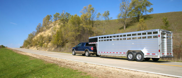 Featherlite livestock trailer hauled by pickup truck on country road