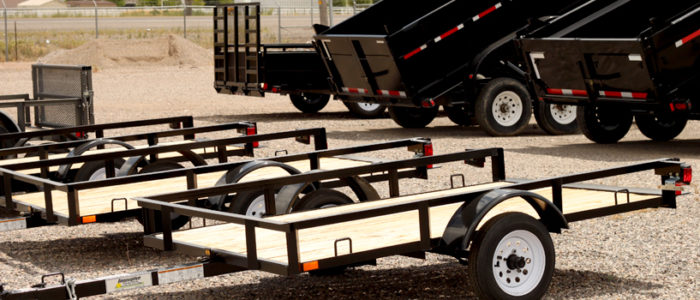 Open utility trailers with dump trailers in background