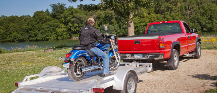 Motorcycle being driven onto an open motorcycle trailer