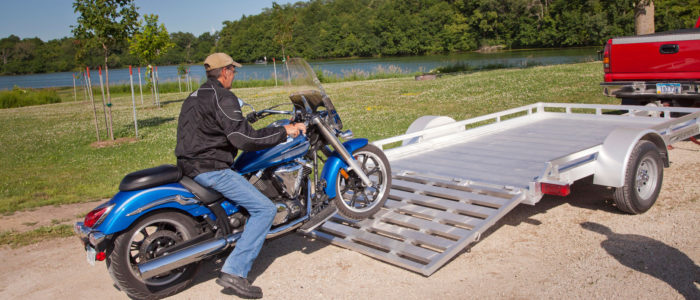 Motorcycle being driven onto an open motorcycle trailer